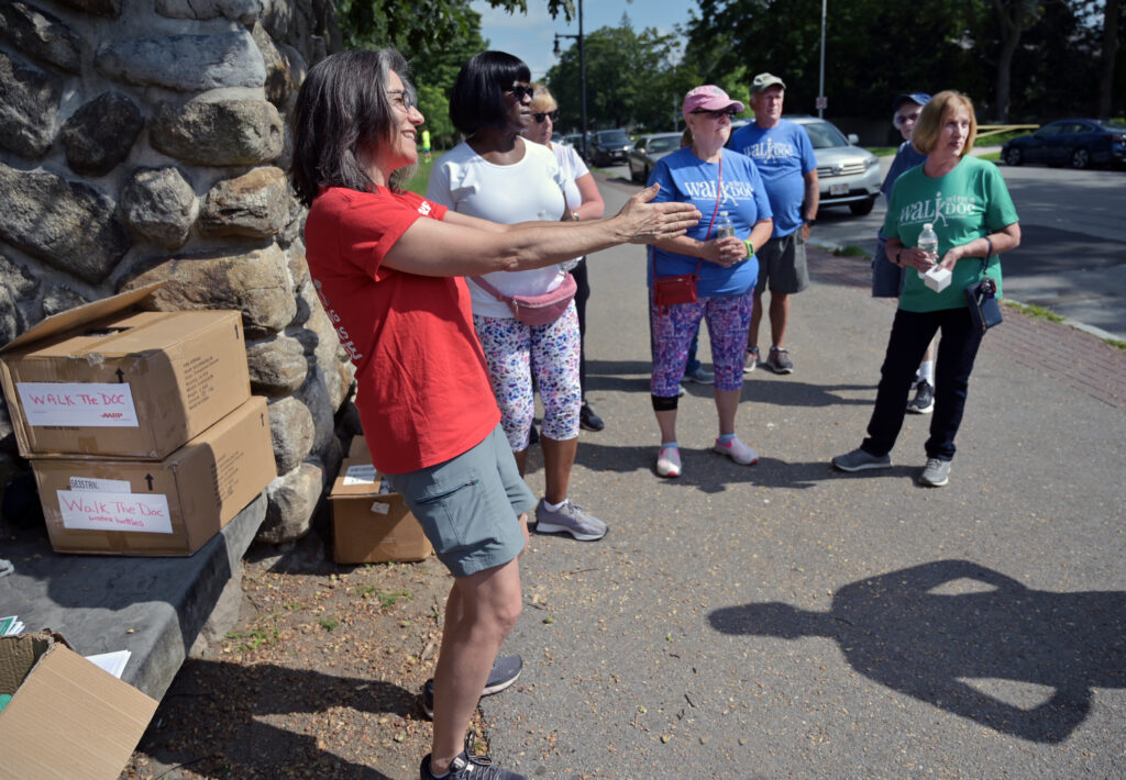 AARP manager for community outreach, Kara Cohen (in red), chats with walkers outside of Elm Park and throws the program over to Dr. Hirsh prior to the “Walk with a Doc” event.